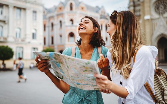 Zwei Urlauberinnen schauen lachend auf Stadtkarte