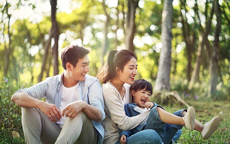 Lachende Familie im Wald sitzend